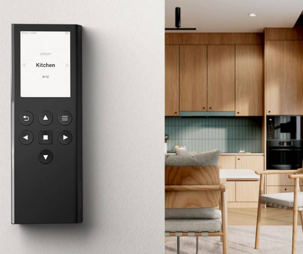 Showing a sleek remote device for automated shades mounted on a wall near a modern kitchen.