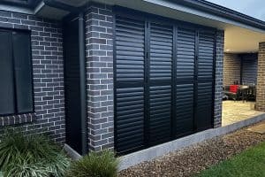 Showing black aluminium shutters installed on an exterior wall, adding privacy and modern style to the home.