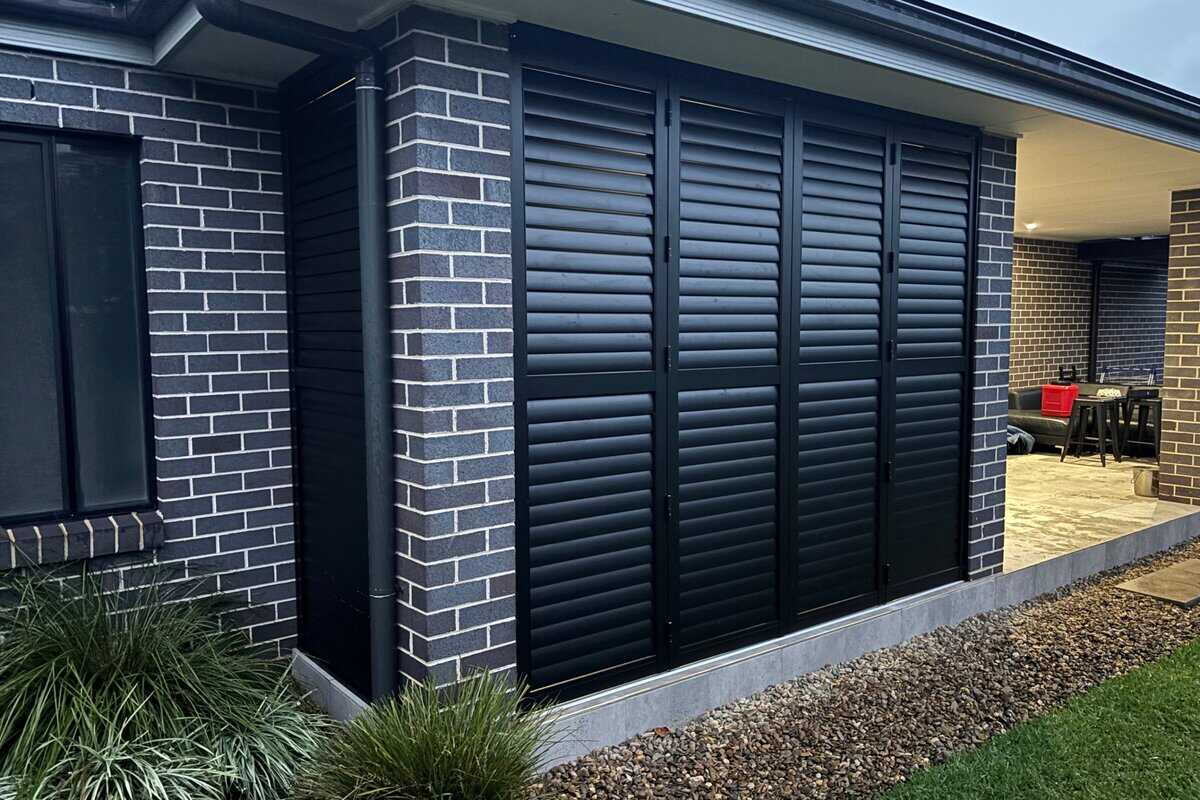 Showing black aluminium shutters installed on an exterior wall, adding privacy and modern style to the home.