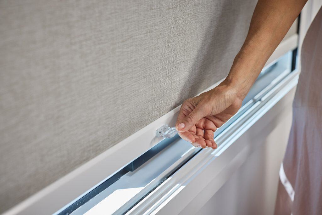 Showing cordless roller blinds safety handle being adjusted by hand
