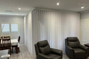 Showing corner vertical blinds installation in a modern living and dining area.