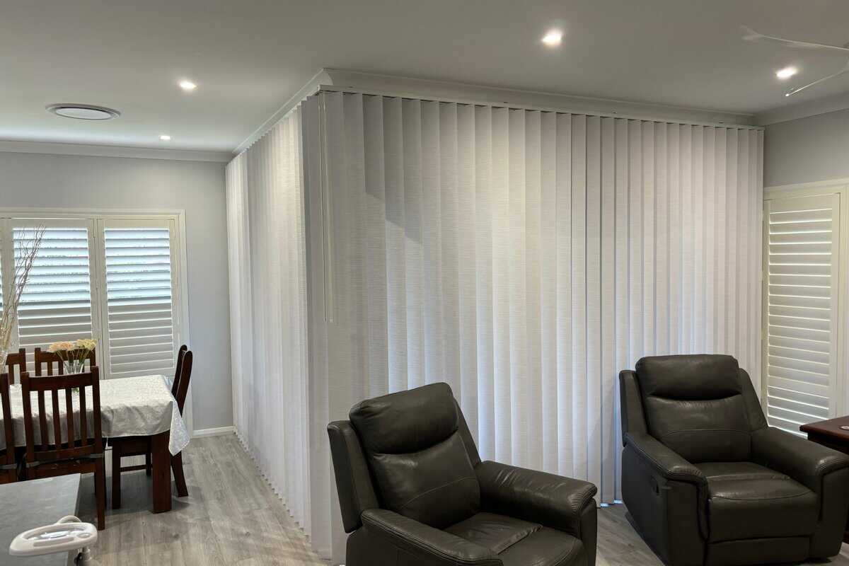 Showing corner vertical blinds installation in a modern living and dining area.