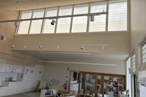 Showing high-window-school-blinds filtering sunlight in a bright classroom space.