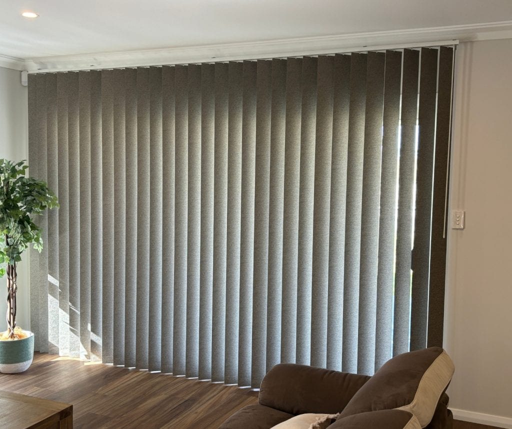 Showing lounge vertical blinds across wide windows with soft natural light.
