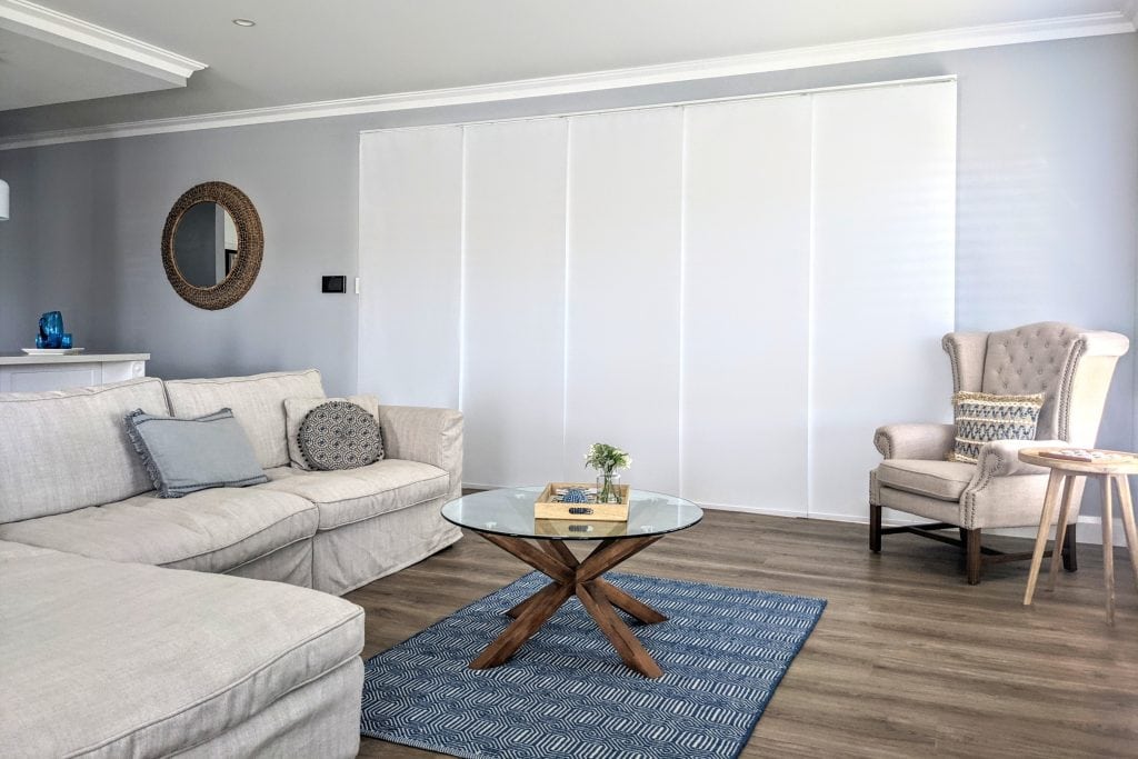 Showing panel glide blinds in a modern living area with wide windows