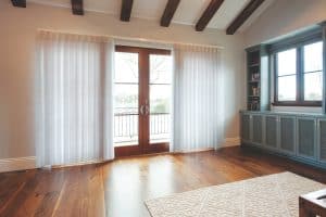 Showing SmartDrape shades across French doors in a bright living room with timber floors.