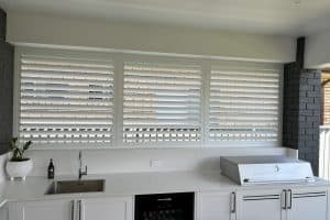 Showing weatherproof aluminium shutters fitted in a sleek outdoor kitchen area for privacy and airflow control.