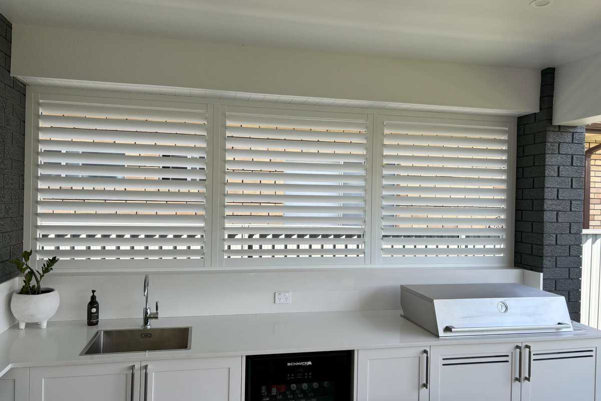 Showing weatherproof aluminium shutters fitted in a sleek outdoor kitchen area for privacy and airflow control.