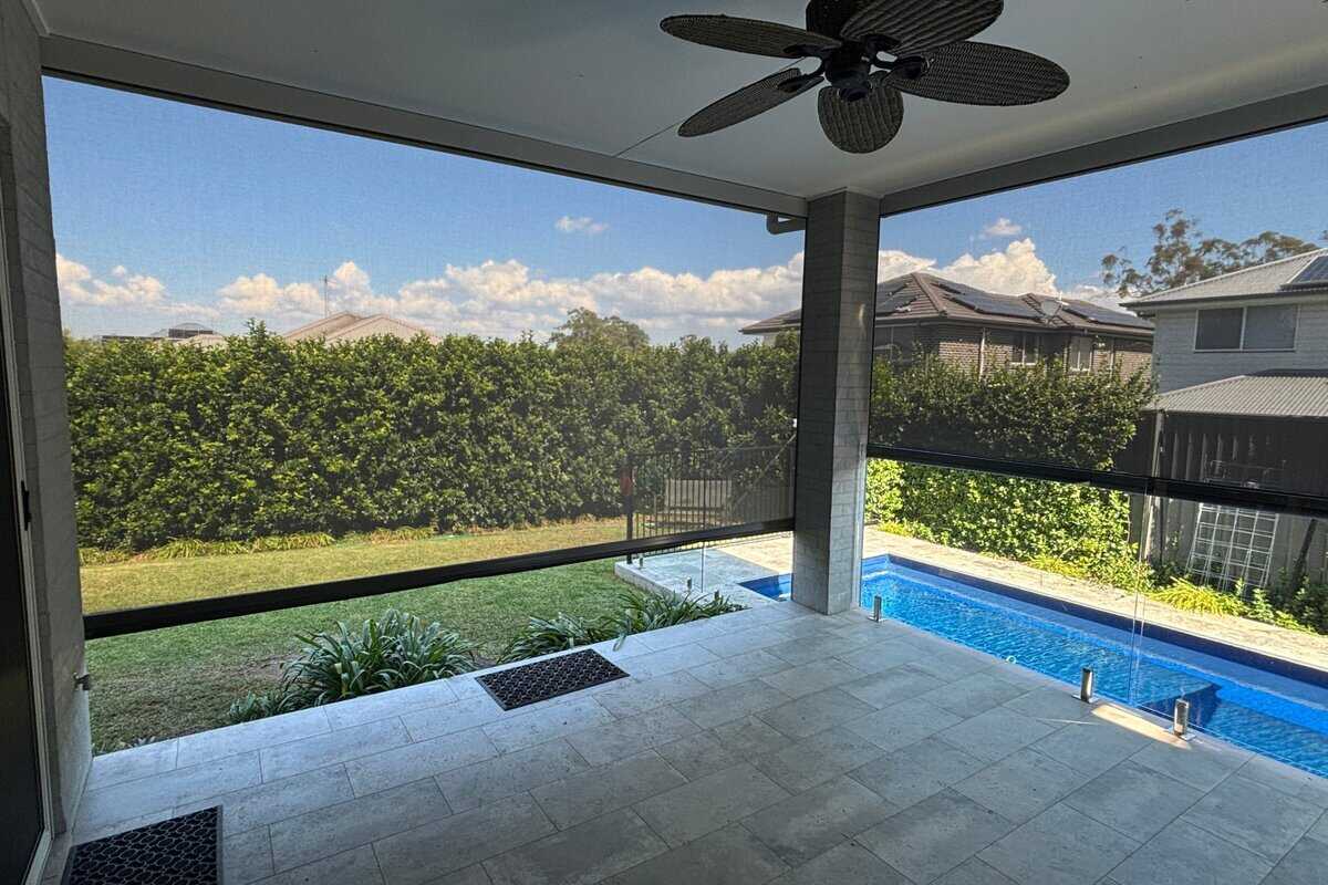 Showing sleek zipscreen outdoor blinds shading a poolside patio for privacy and weather protection