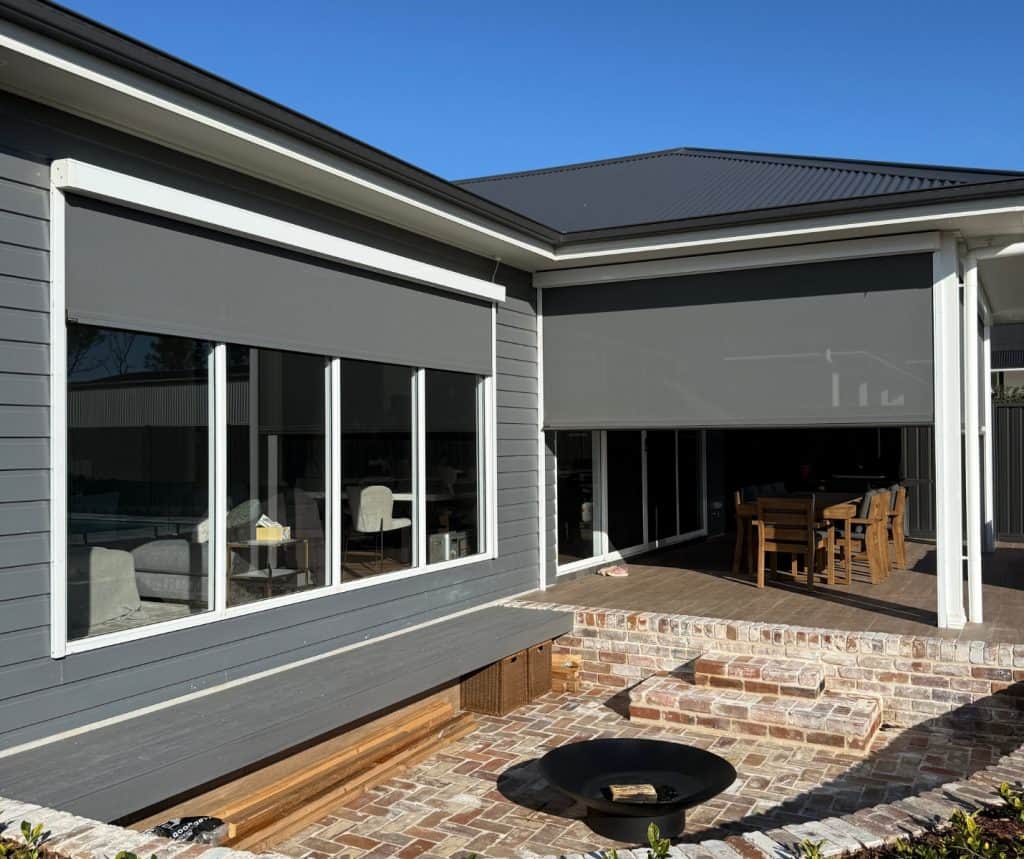 Showing motorised exterior blinds installed on windows and patio area of a modern single-storey home