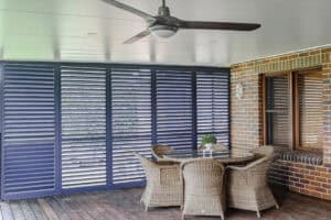 Showing Ocean Blue aluminium plantation shutters enclosing an alfresco entertaining area, providing shade, privacy and airflow.