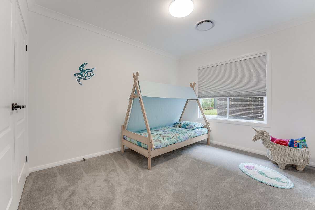 Showing a children's bedroom with custom cellular blinds, soft carpeting, a timber bed frame and filtered natural light.