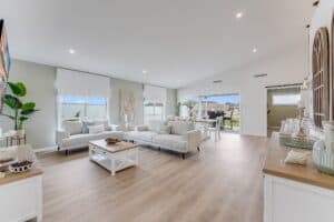 Showing an open-plan living and dining area with white Roman blinds, neutral furnishings and abundant natural light.