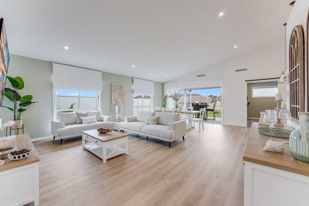 Showing an open-plan living and dining area with white Roman blinds, neutral furnishings and abundant natural light.
