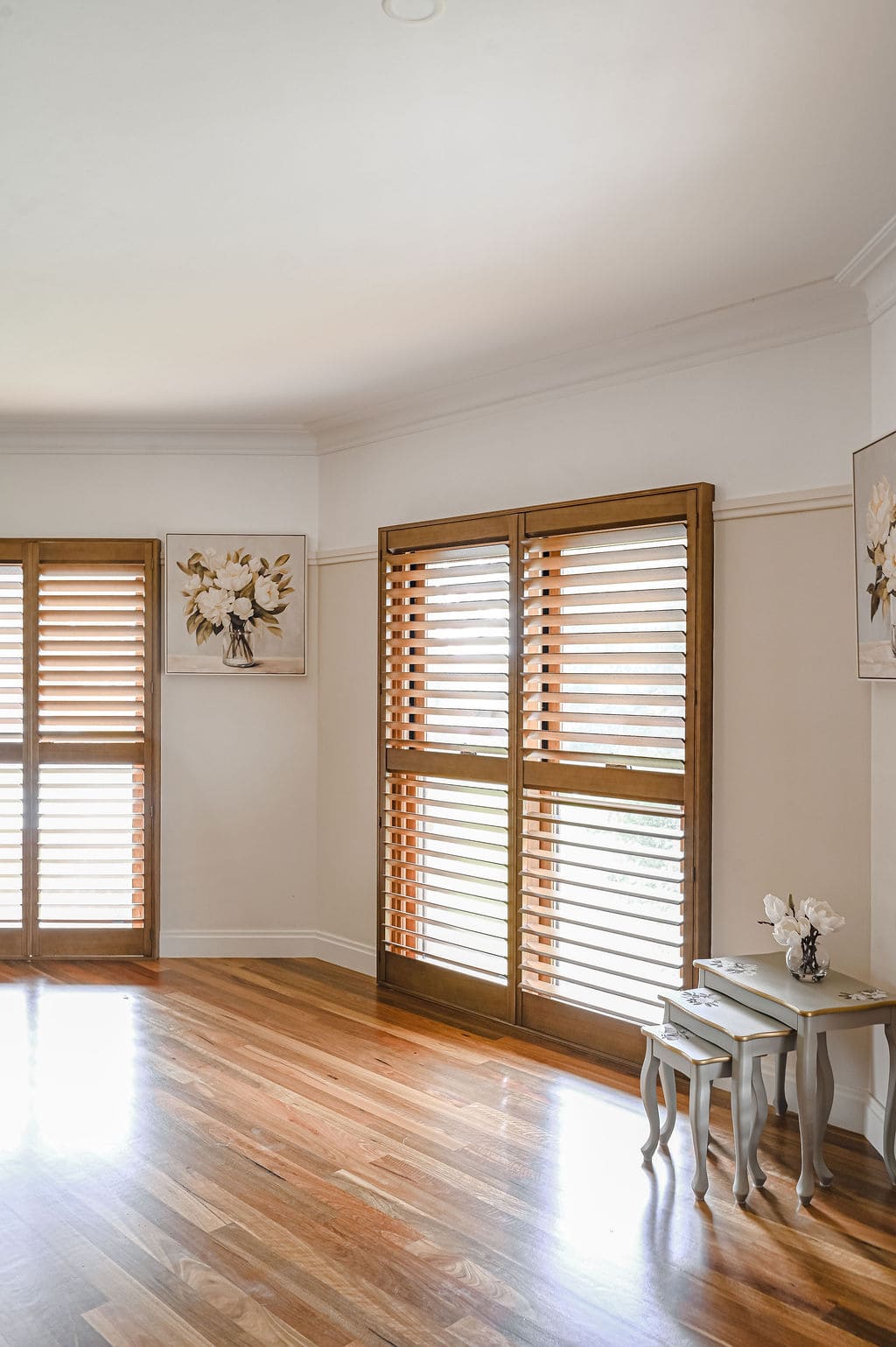 Showing real timber heritage window shutters with a natural woodgrain finish, providing light control in a timeless living room.