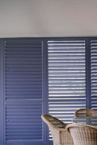 Showing Ocean Blue aluminium plantation shutters enclosing an alfresco area, providing privacy, shade and weather protection.