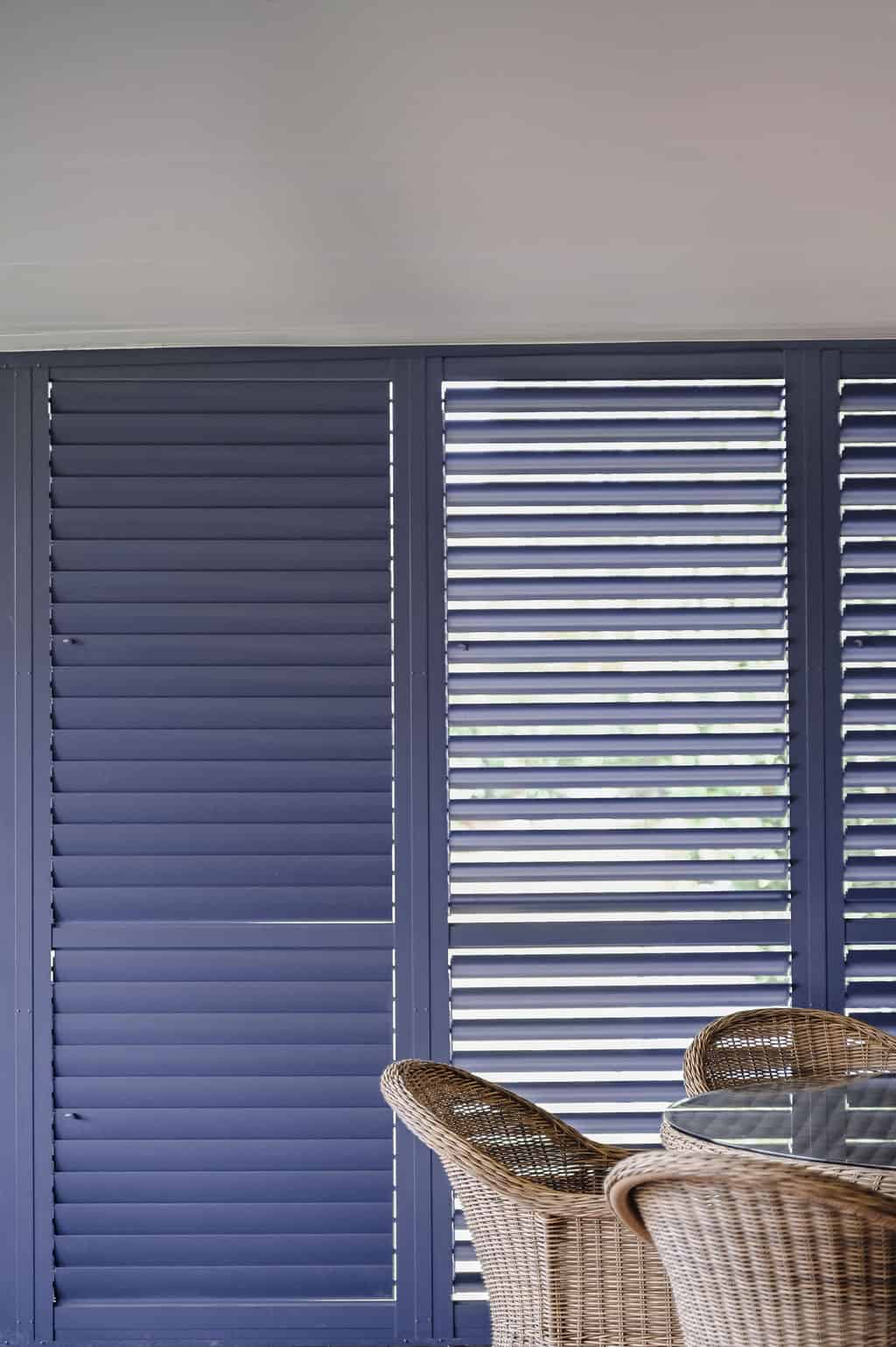 Showing Ocean Blue aluminium plantation shutters enclosing an alfresco area, providing privacy, shade and weather protection.