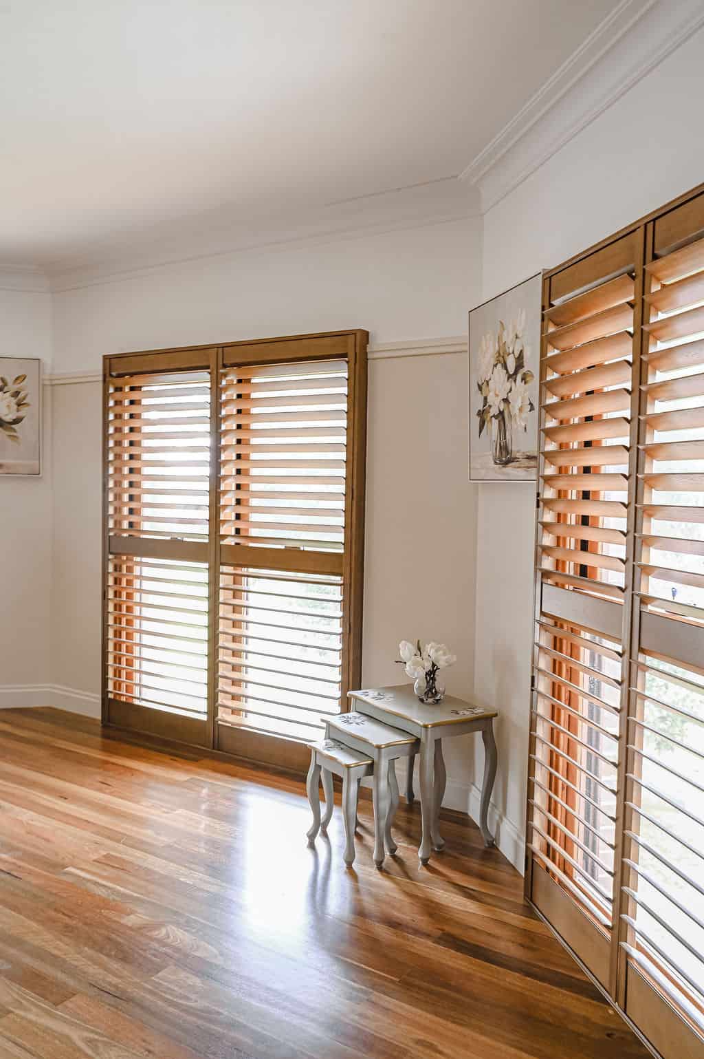 Showing real timber plantation shutters with natural woodgrain finish in a heritage-style living room, filtering natural light