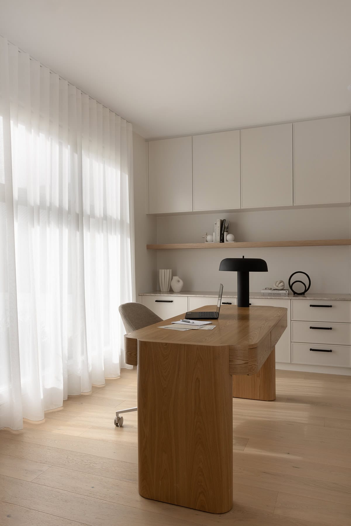 Showing a roller blind and sheer curtains in a modern home office, providing filtered natural light, privacy and a calm workspace.