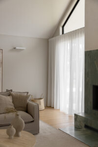 Showing floor-to-ceiling sheer curtains in a modern lounge room, filtering natural light while creating a soft, private and welcoming space
