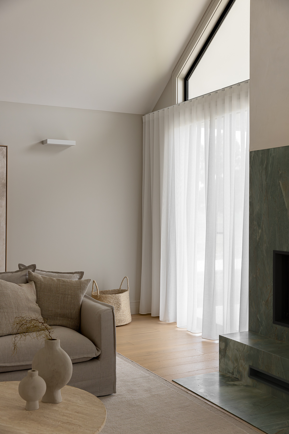Showing floor-to-ceiling sheer curtains in a modern lounge room, filtering natural light while creating a soft, private and welcoming space