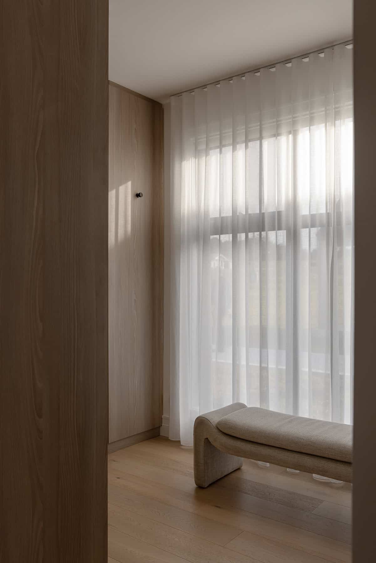 Showing floor-to-ceiling sheer curtains in a modern walk-in robe, filtering natural light to create a soft and private space.
