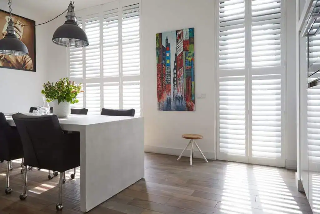 White plantation shutters on full-height doors in a dining area